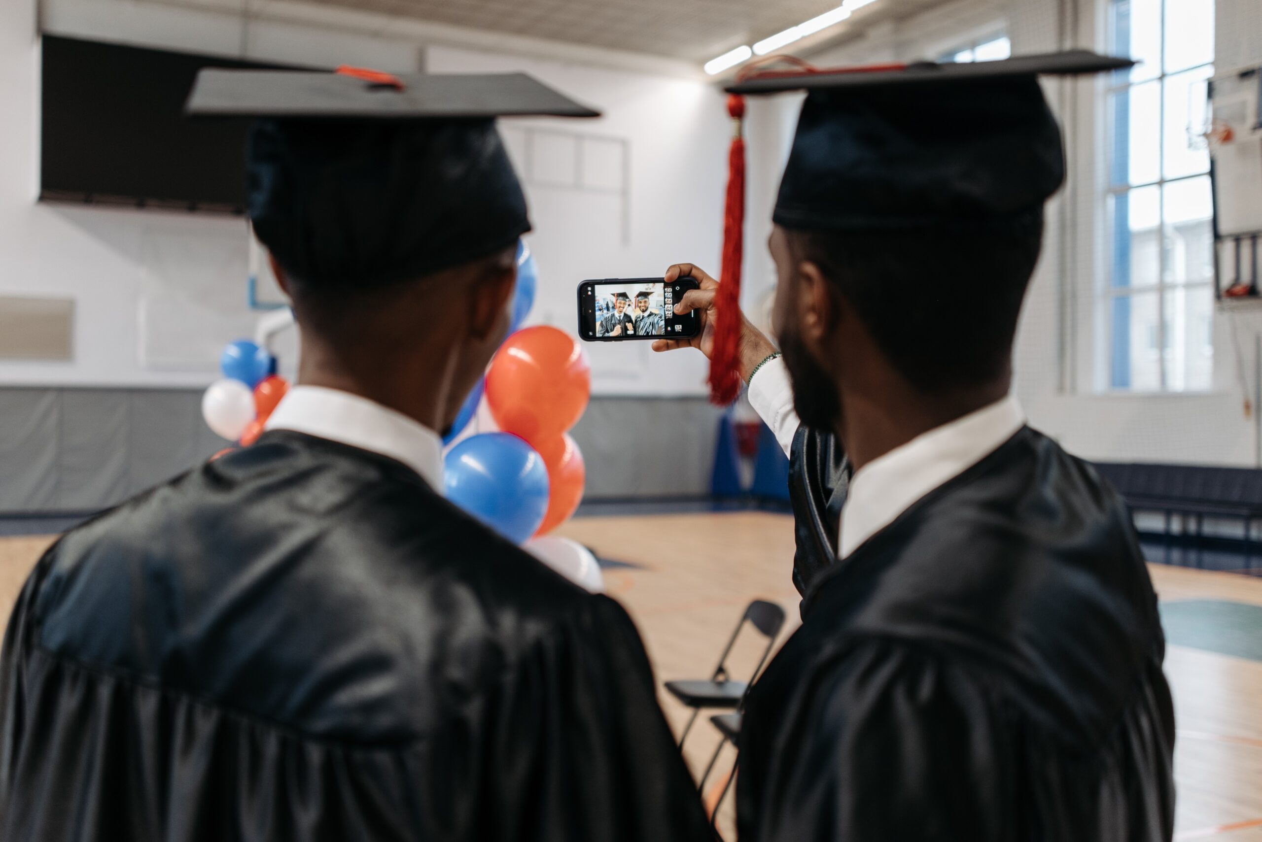 Friends taking a selfie with their phone in their graduation dress