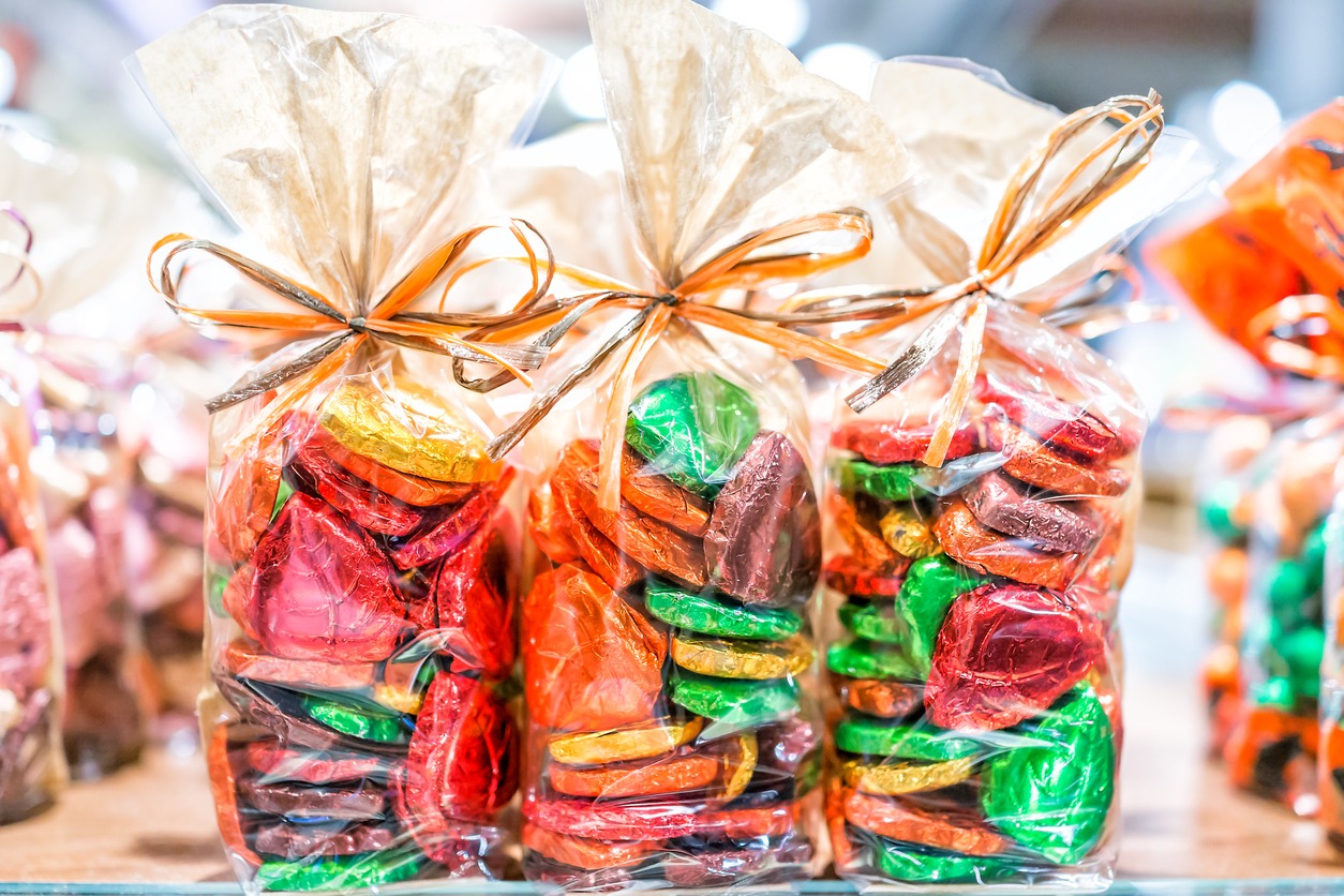 Colorful packaged wrapped chocolate hearts in candy store shop, green, golden, gold, yellow as gifts, tied in bags ribbons red foil holiday