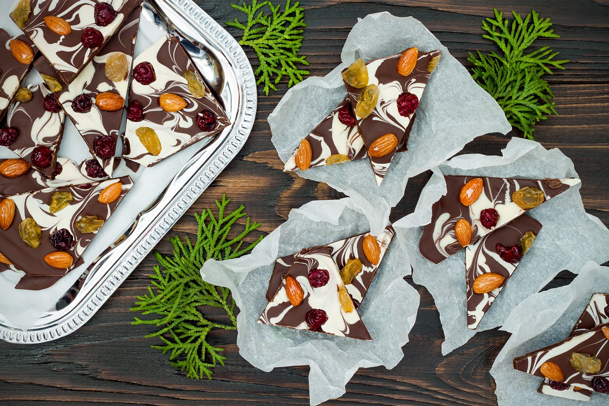 Holiday chocolate bark with dried fruits and nuts on a dark wood background
