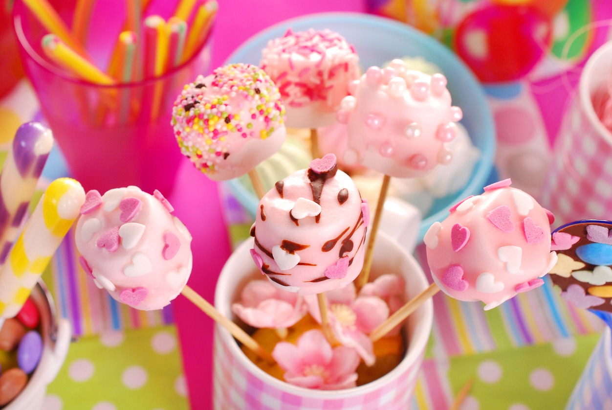 colorful birthday party table with homemade pink marshmallow pops and other sweets for kids