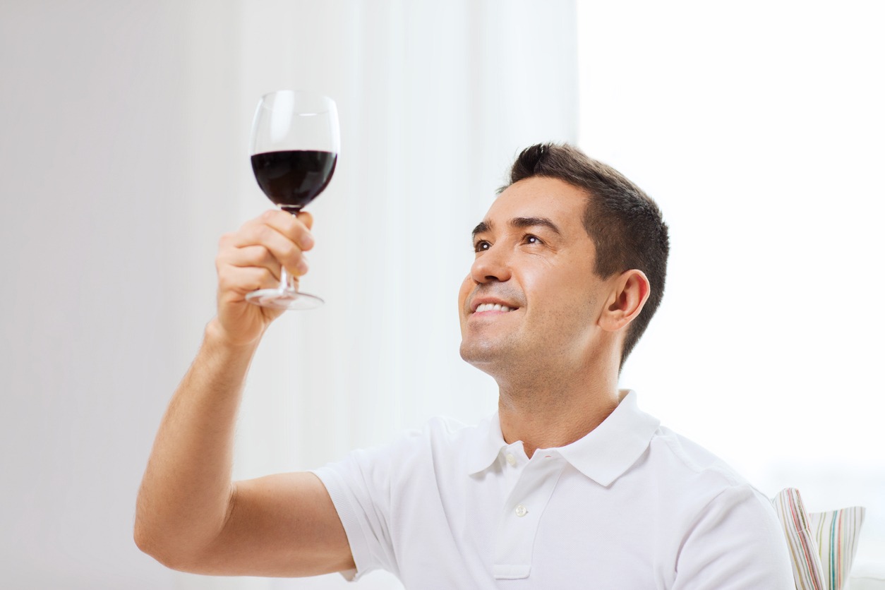  profession, drinks, leisure and people concept - happy man drinking red wine from glass at home