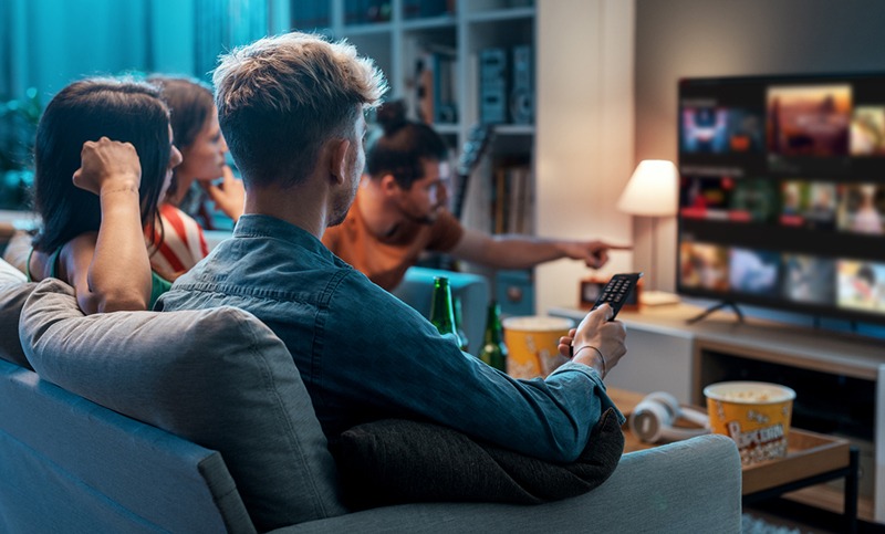 Group of friends watching a game on TV with drinks in their hands 