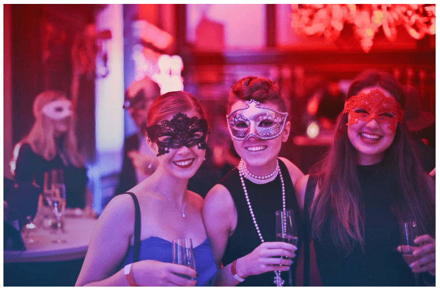 Group of women wearing classy outfits and decorative masks 