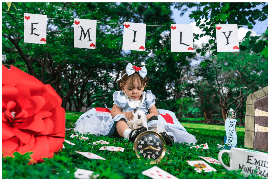 a little girl wearing and surrounded by alice in wonderland-themed stuff