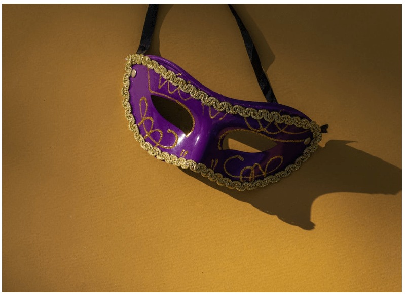 a purple mask hanging on a yellow wall