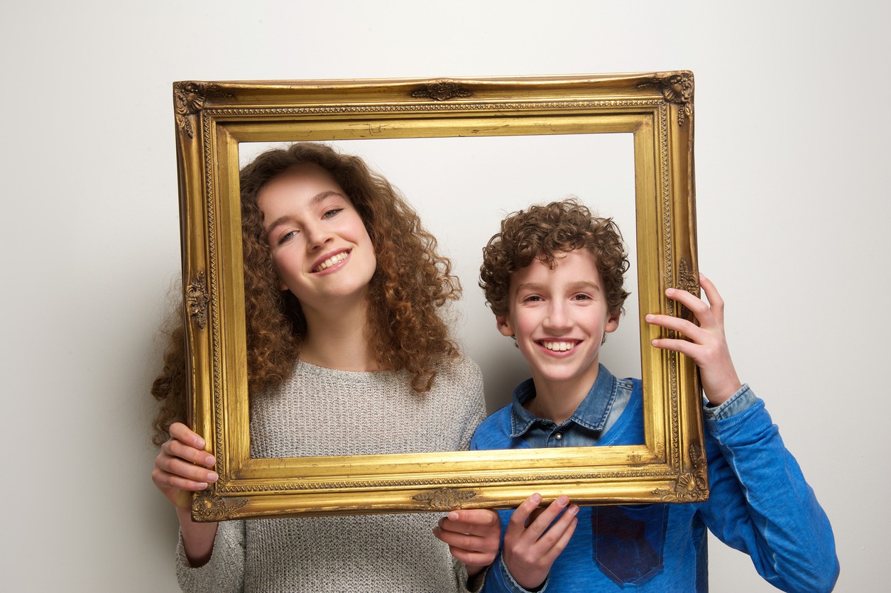 Portrait of a happy brother and sister holding picture frame