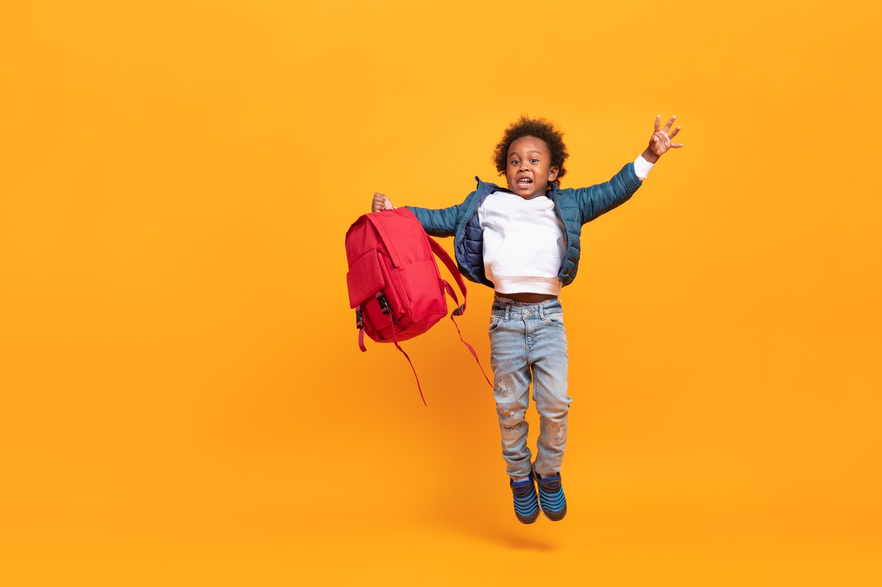a boy jumping with a red school bag