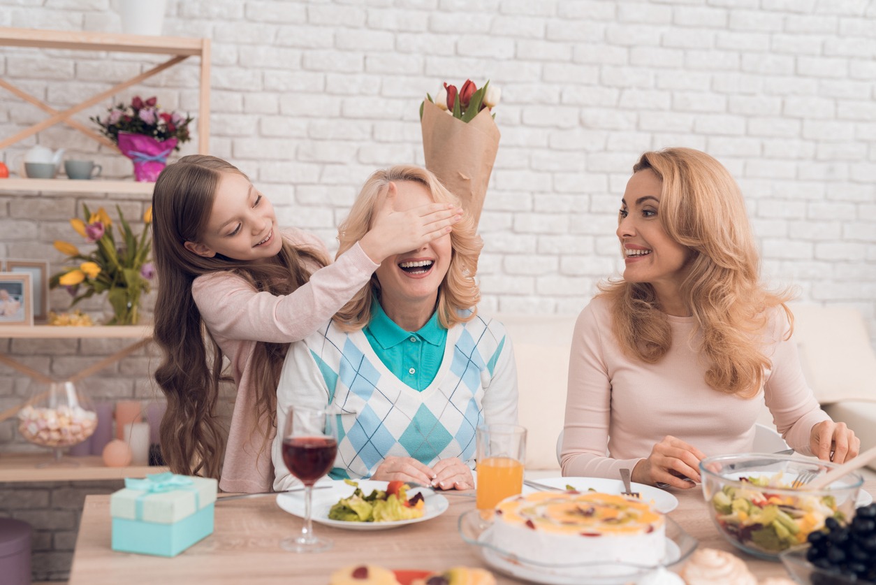 Mother happily receiving gifts from kids at lunch table