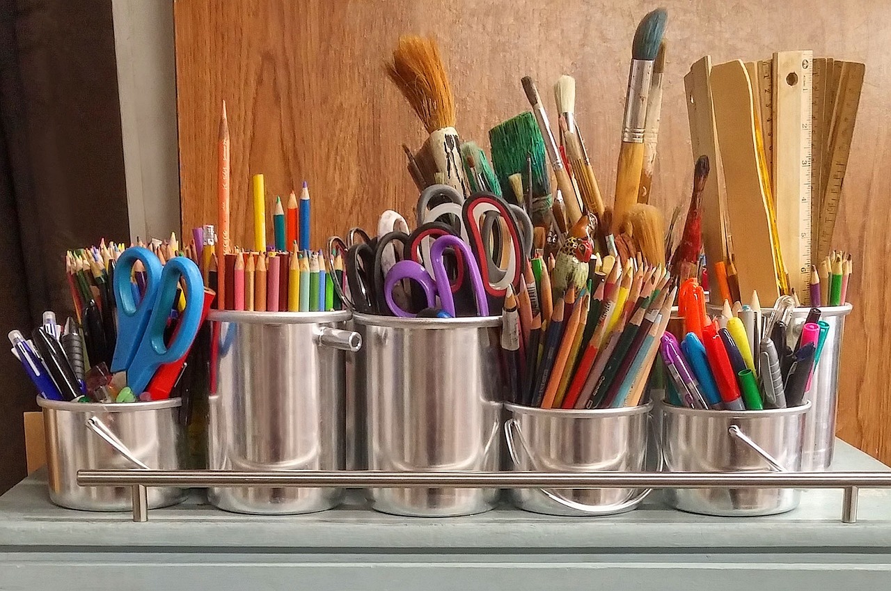 different colored paints and different sized paint brushes in metal buckets