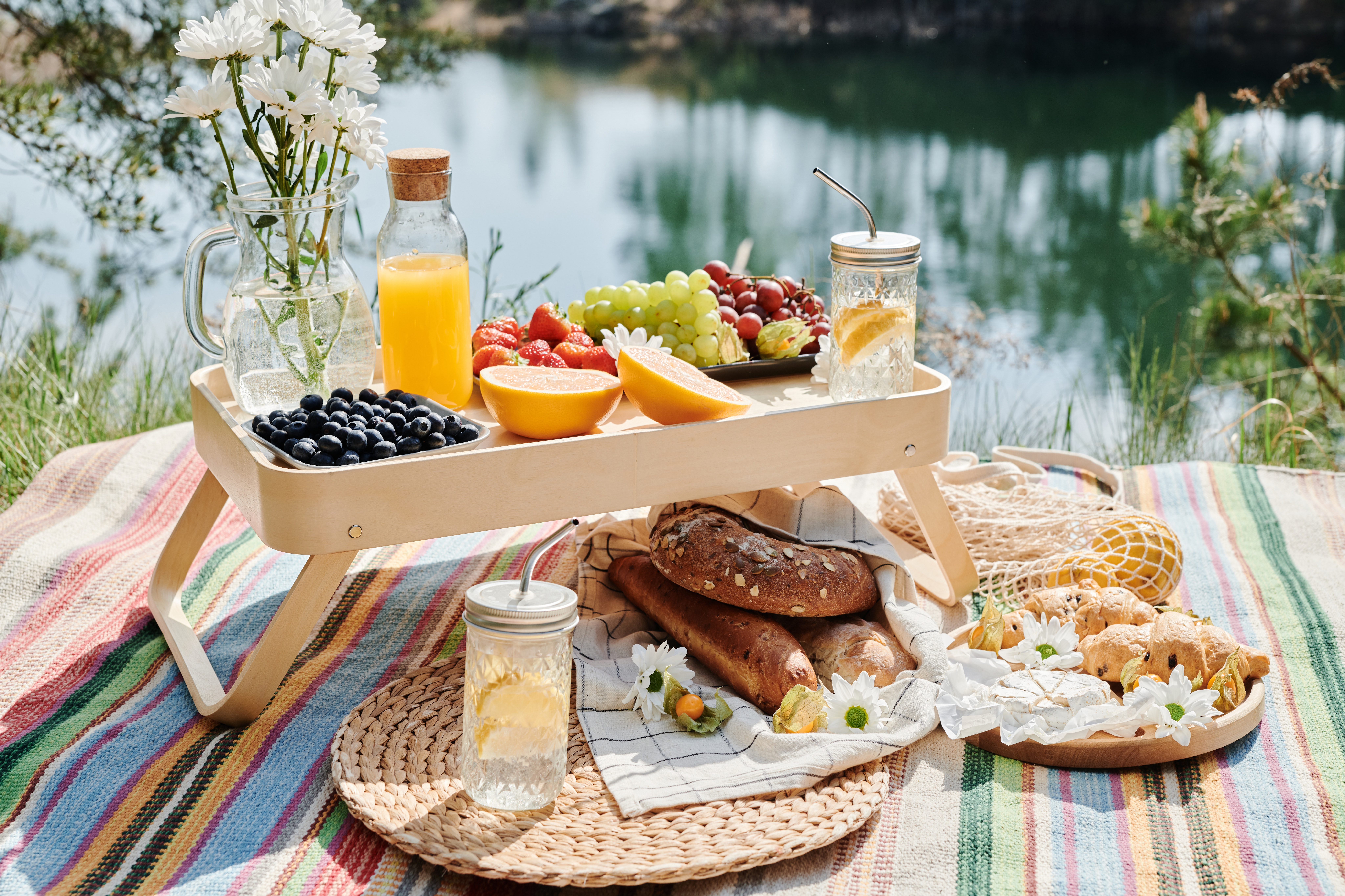 picnic food and drinks on a blanket and a tray