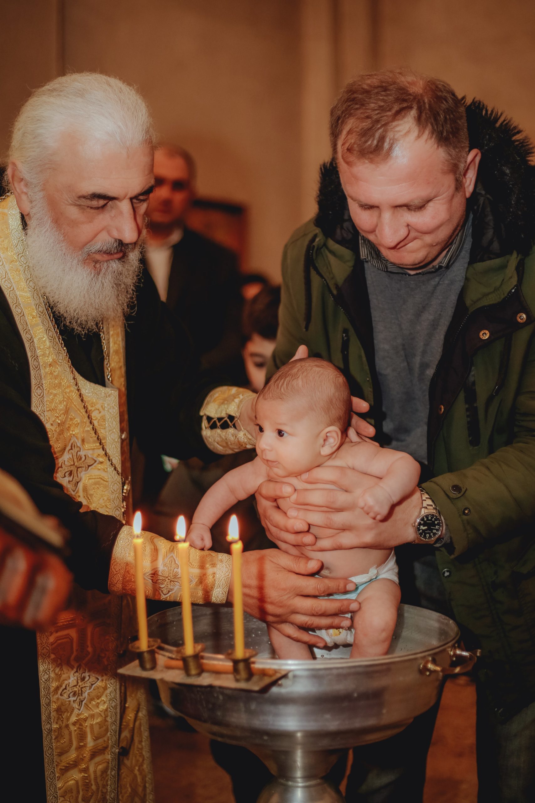 priest christening a baby held by the father