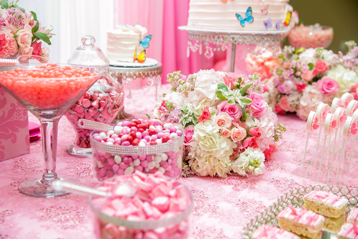 Dessert table with a cake topped with ballerina-themed elements and other pink-colored sweets 