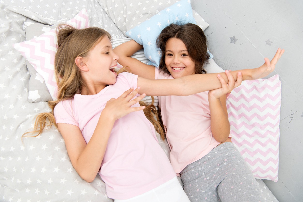 Happy little girls lying on a bed during slumber party 