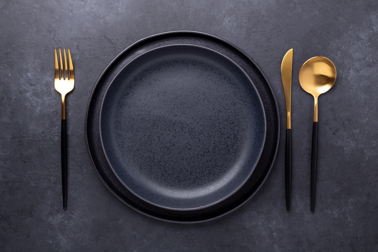 Dark table setting. Two empty ceramic plates and cutlery on stone background Copy space for your text - Image