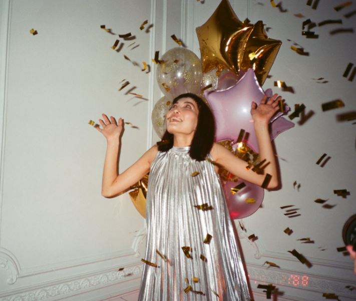 woman being surprised by balloons and confetti