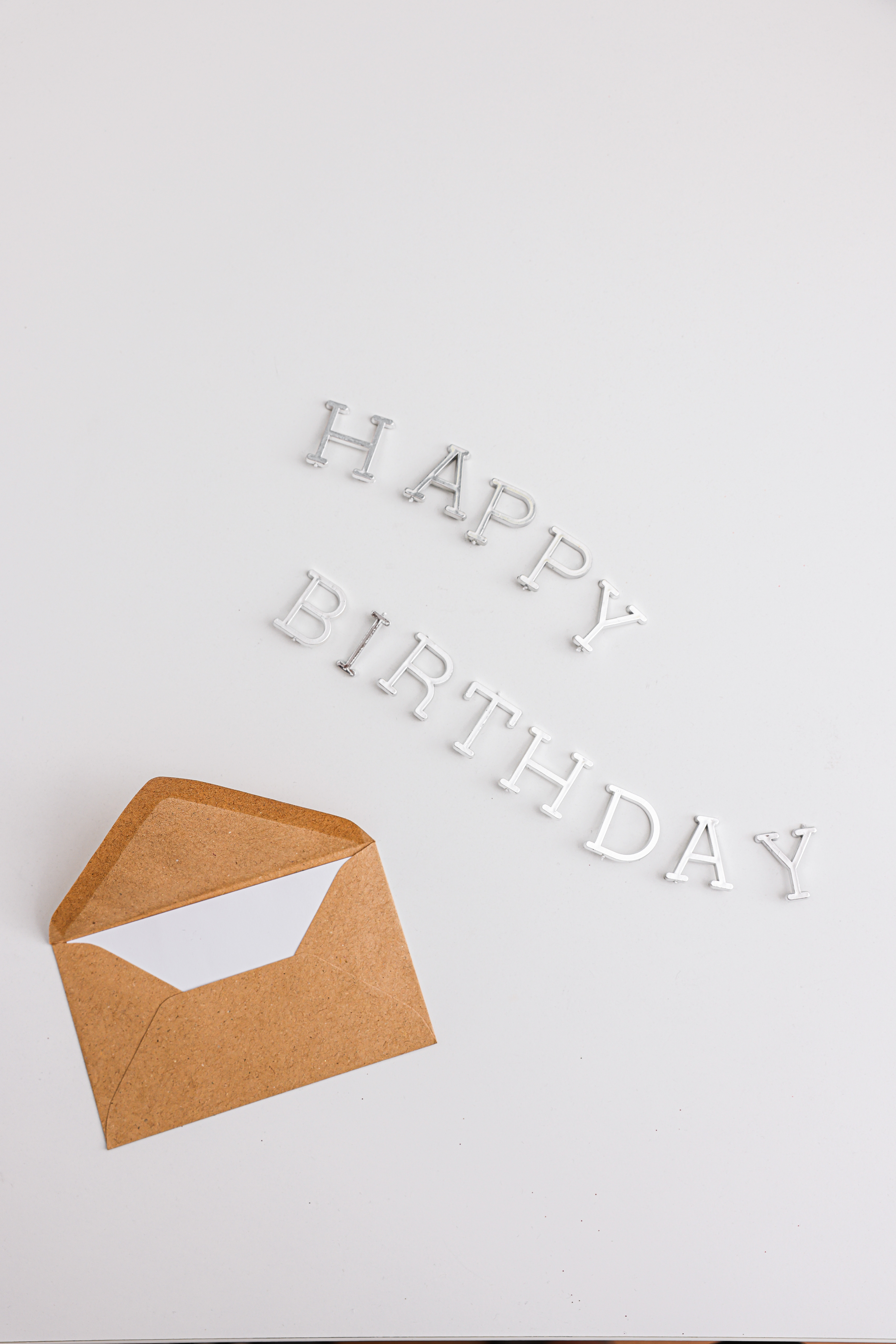 a brown envelope with a letter inside beside plastic letters spelling “Happy Birthday”