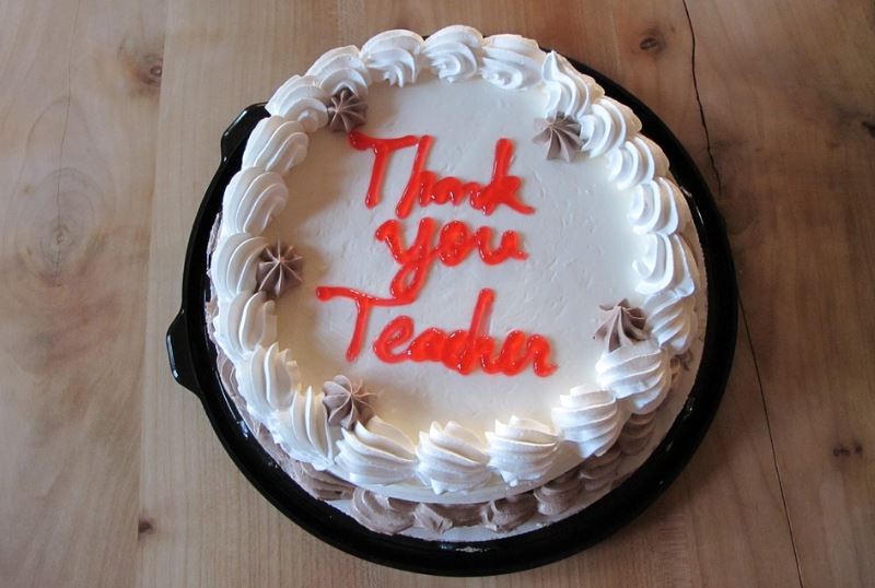 a white cake with a “Thank you Teacher” written in red icing