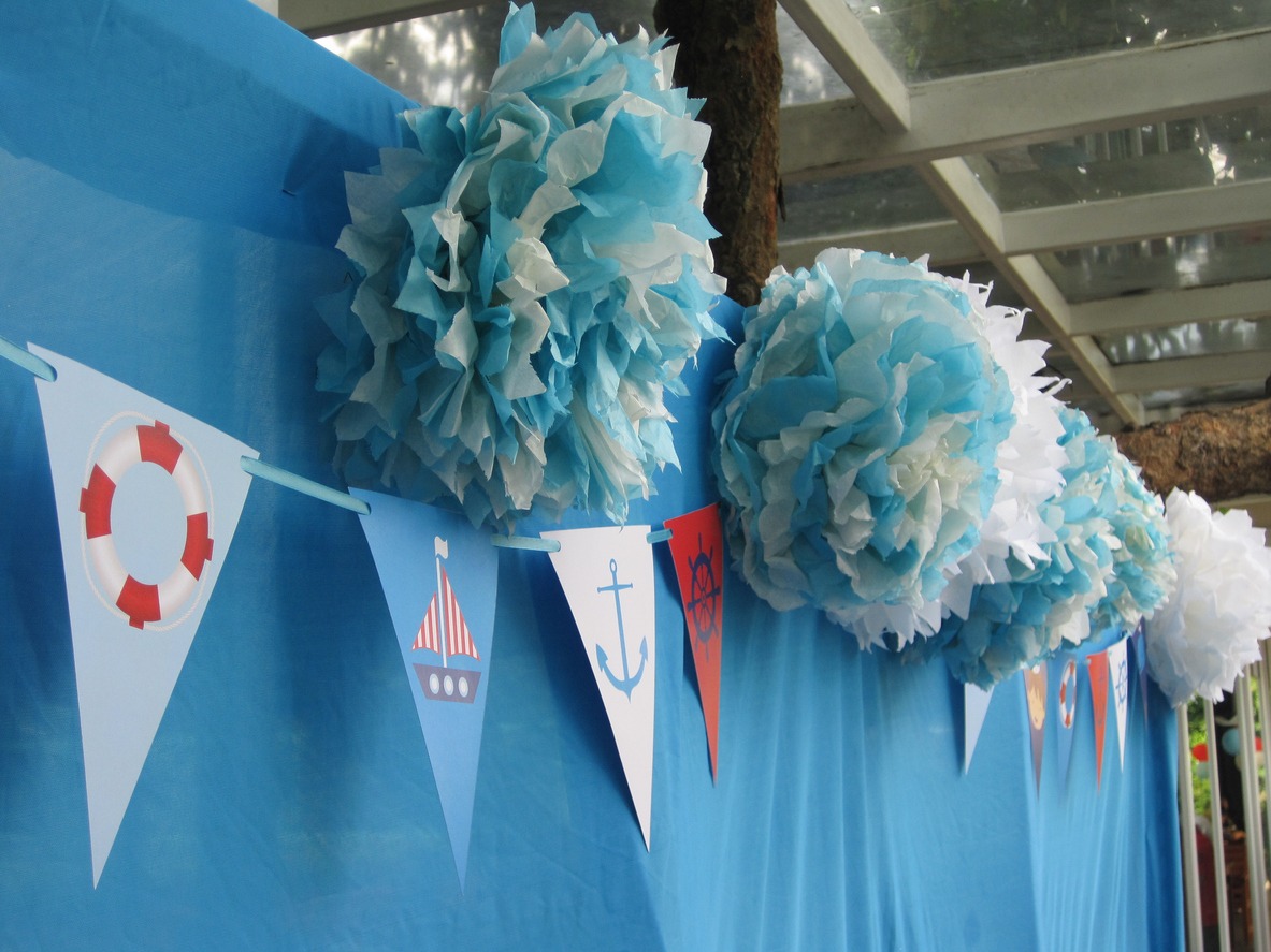 Boat-themed-pennant-banners-and-blue-and-white-pompoms-decorating-a-party