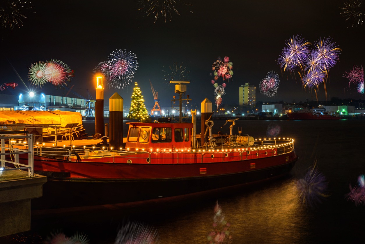 a boat against fireworks over the river in the city.