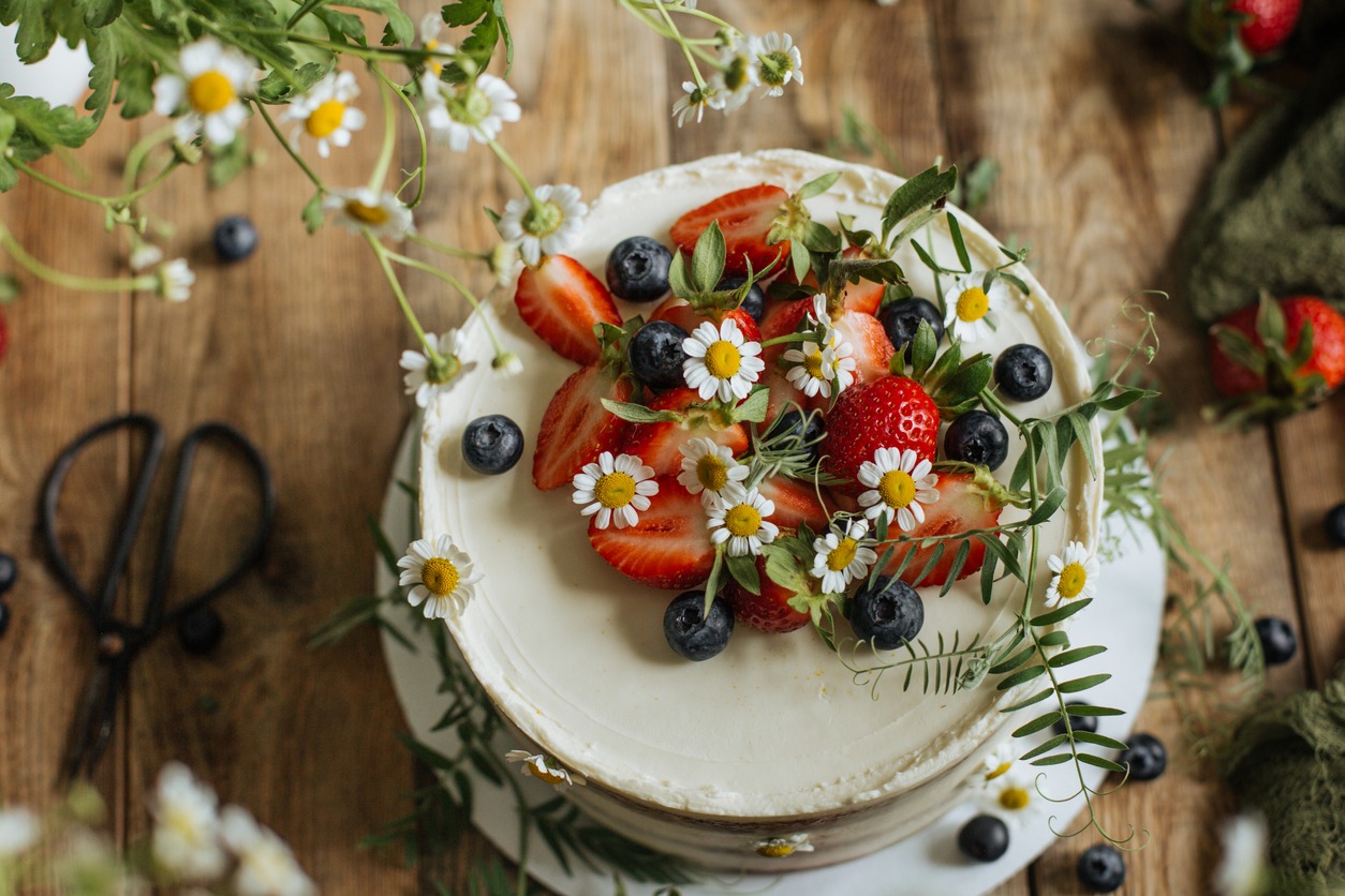 a cake decorated with berries and flowers on a table