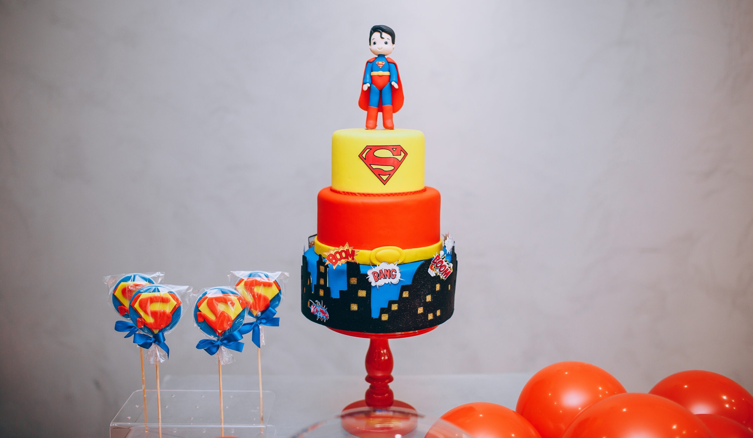 Superman themed lollipops and cake with a Superman topper