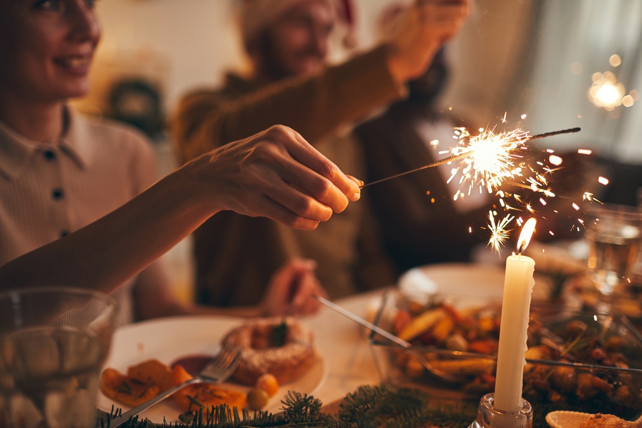 Close up of hand holding sparkler over Christmas dinner background