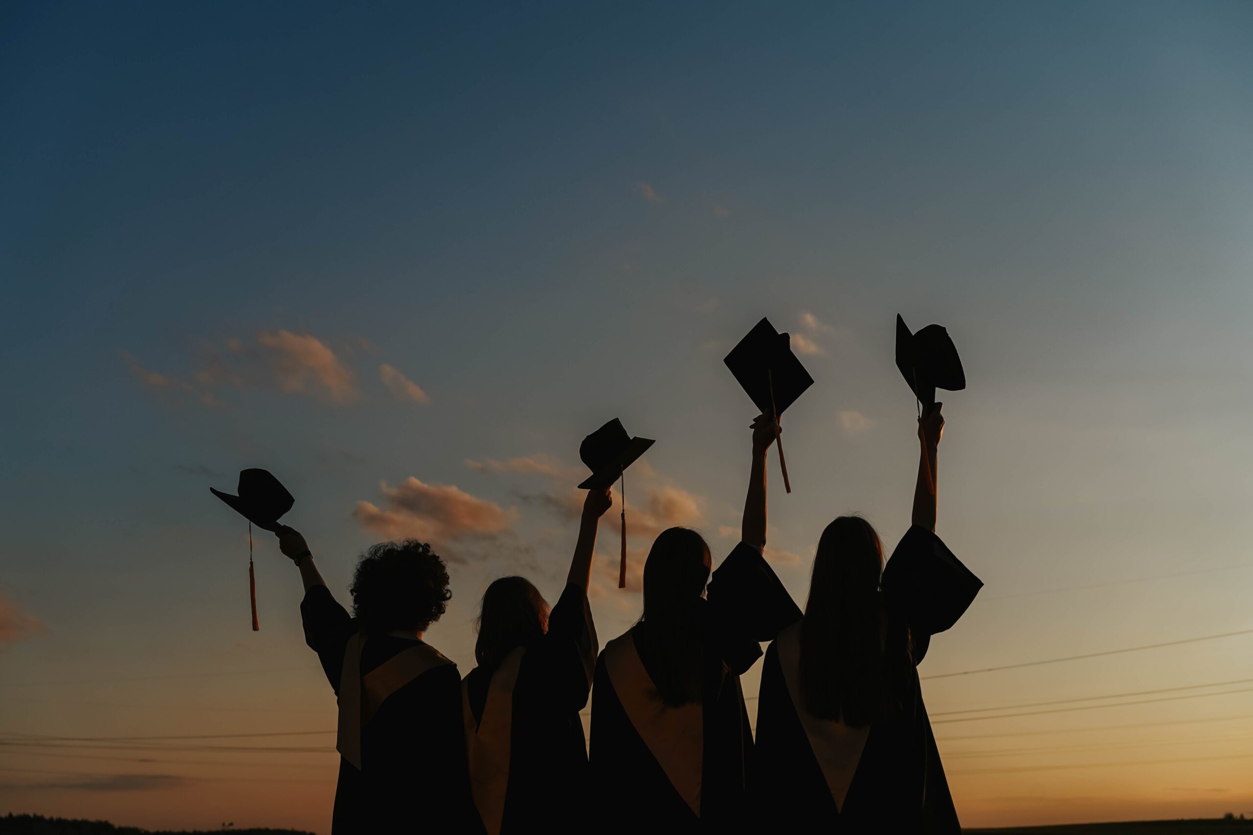 picture of graduates raising their graduation hats 