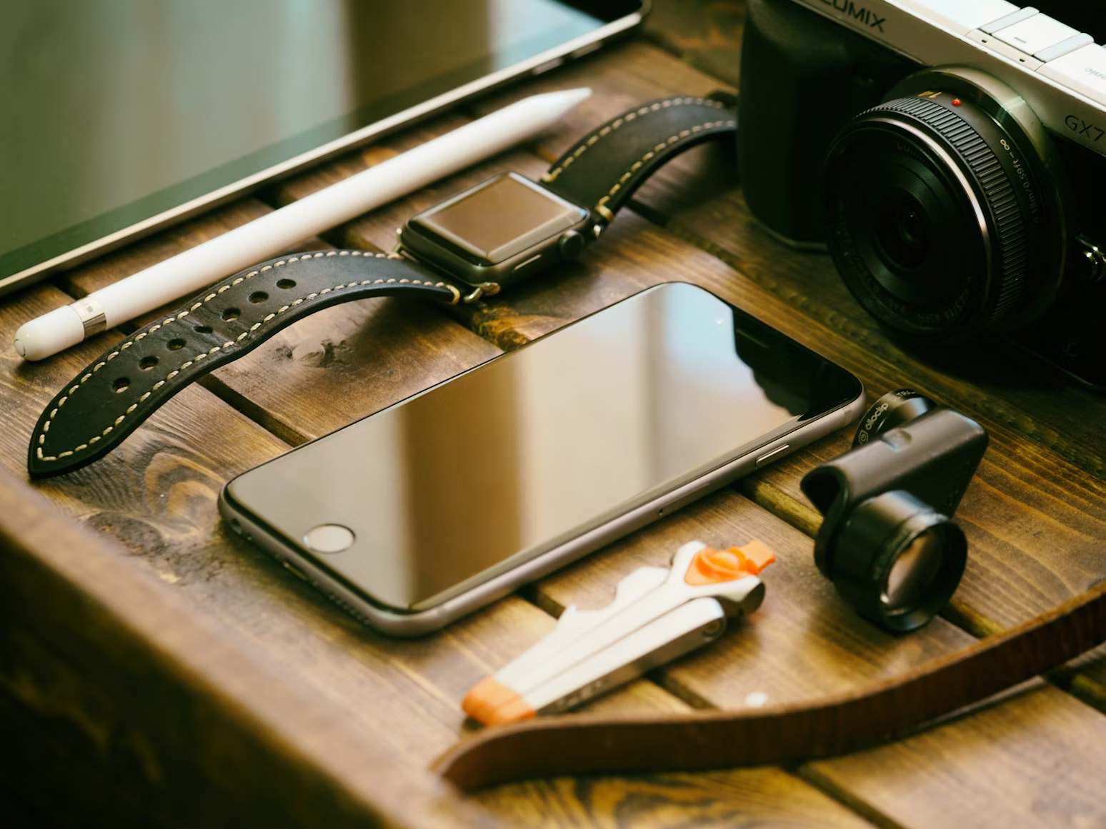 Phone, lens and camera on a wooden table